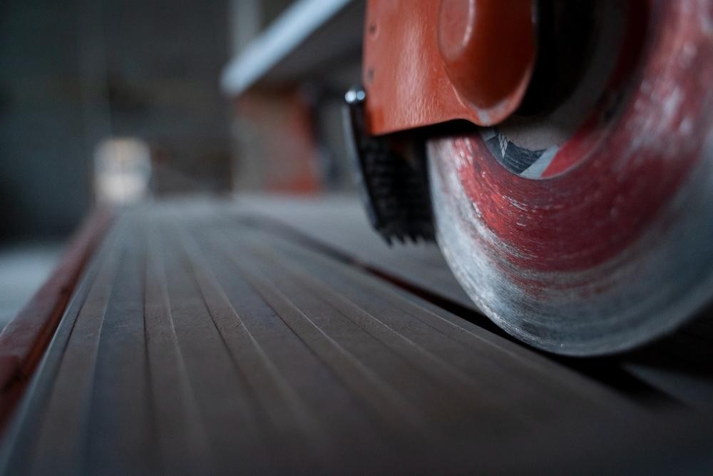 Primer plano de una rueda abrasiva montada en una máquina industrial, en contacto con una superficie plana para realizar corte o pulido.